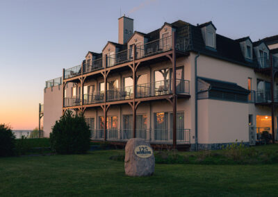Rückseite des Hotels mit Holzbalkonen bei Abendlicht.