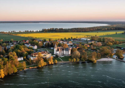 Luftaufnahme des Hotels an der Müritz mit angrenzenden Häusern und grünen Uferbereichen – zeigt die naturnahe Lage des Standorts. Abendstimmung