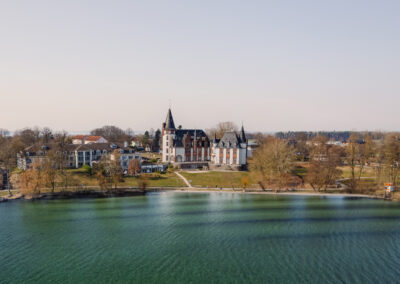 Luftaufnahme des Hotels an der Müritz mit angrenzenden Häusern und grünen Uferbereichen – zeigt die naturnahe Lage des Standorts. Abendstimmung